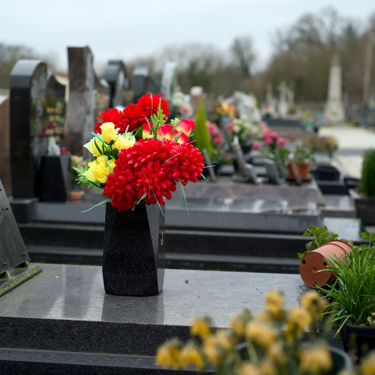 цветы на могиле в вазе из камня